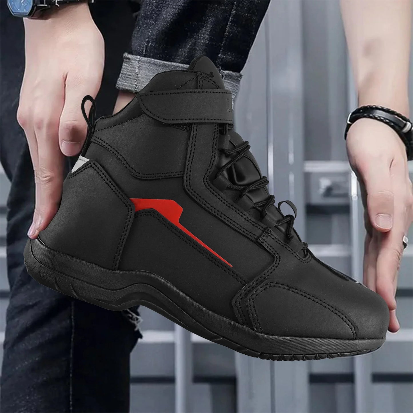 Black high-top sports shoe with red accent, worn by person in jeans